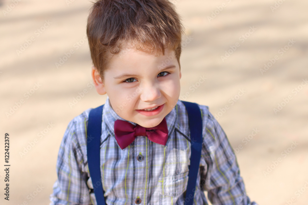 Handsome little boy with bow tie looks at camera outdoor, top vi Handsome little boy with bow tie looks at camera outdoor, top vi