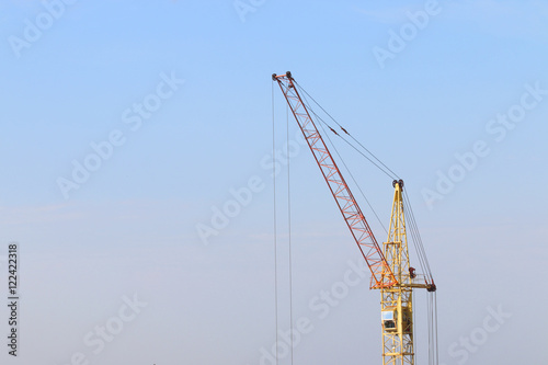 Part of yellow stationary hoist on construction site, blue sky a