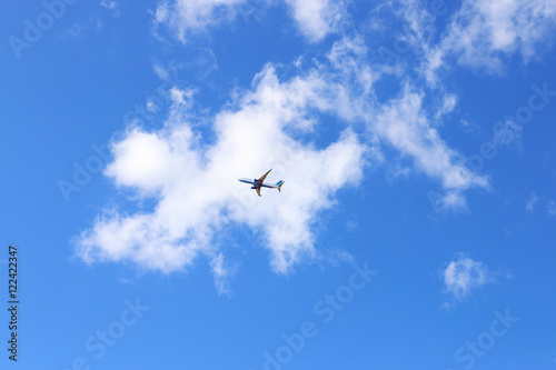 Under view of modern passenger airliner in blue sky with white c