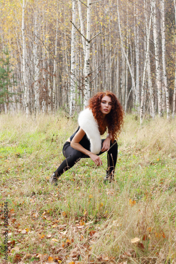 Beautiful woman with white fur poses in autumn forest with birch Beautiful woman with white fur poses in autumn forest with birch