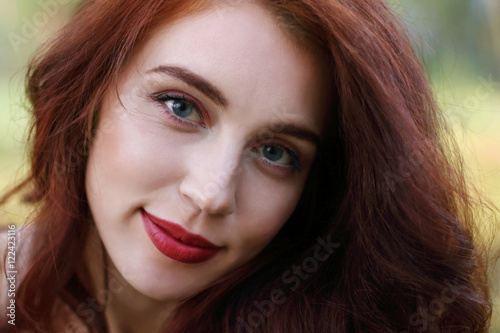 Woman with red hair smiles in forest, shallow dof, close up