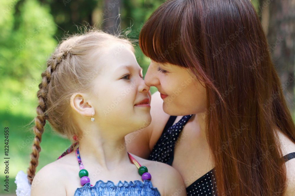 Happy mother and daughter rub noses in park at summer sunny day Happy mother and daughter rub noses in park at summer sunny day