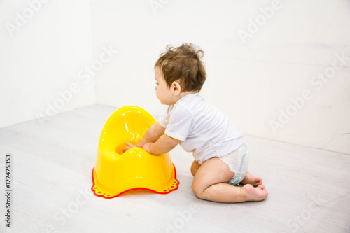 Infant child baby boy toddler play with potty toilet stool pot on a white background