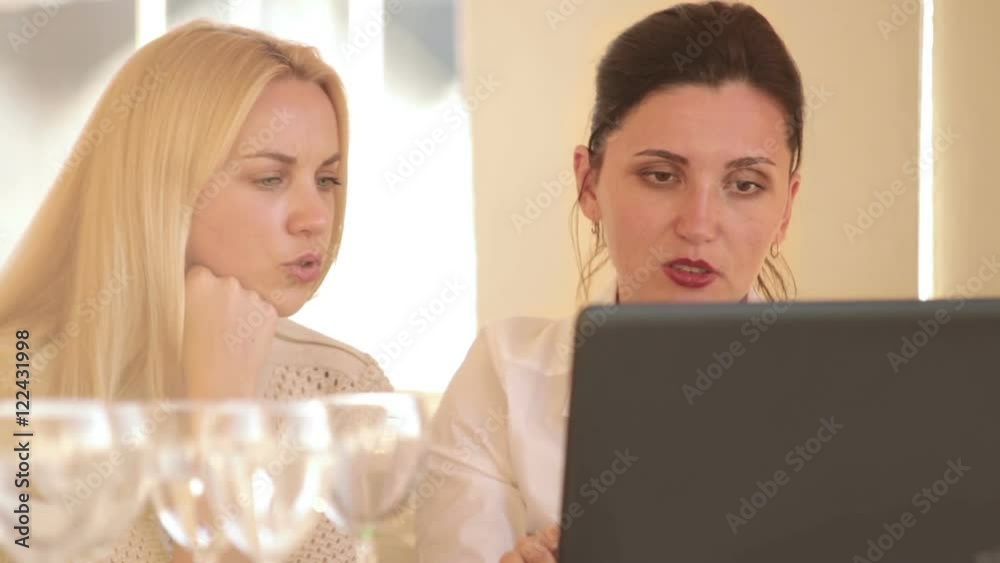Two coworkers business women discussing their restaurant ideas using laptop Two coworkers business women discussing their restaurant ideas using laptop