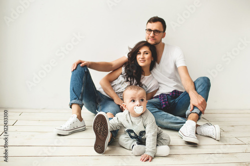 Hipster father, mother holding cute baby boy over white background