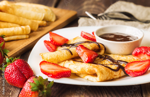 Fresh homemade crepes with strawberries and chocolate sauce photo