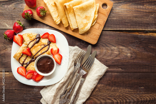 Fresh homemade crepes with strawberries and chocolate sauce photo