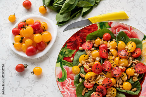 Spinach salad with tomato and nuts. Fresh vitamin salad. Top view.