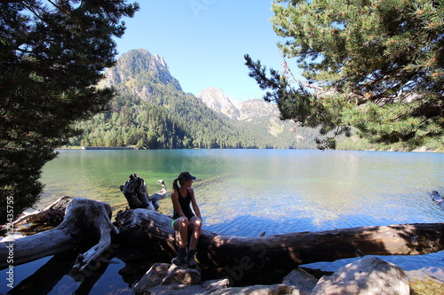 Young beautiful woman restin in Estany de Sant Maurici lake, after a long mrning hike in the Aiguestortes National Park, Pyreness mountains, Catalonia, Spain photo