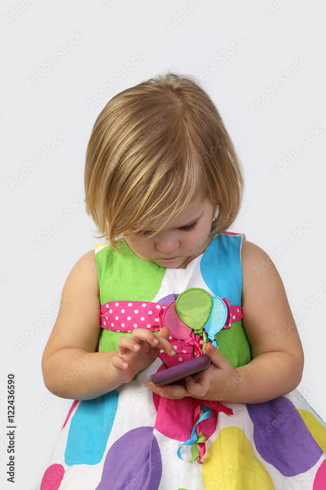 Little girl plays with cell phone close up on gray background Little girl plays with cell phone close up on gray background