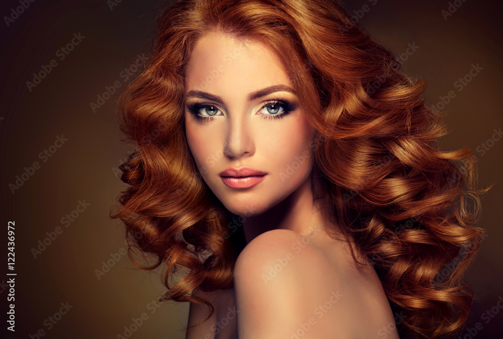 Girl with long  and   shiny wavy  red hair .  Beautiful  model with curly hairstyle .