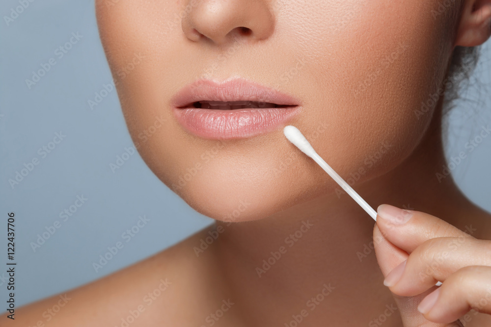 Woman with a cotton swab beside her lips