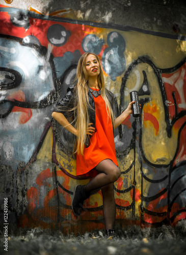 beautiful girl with long hair in a red dress on background of graffiti