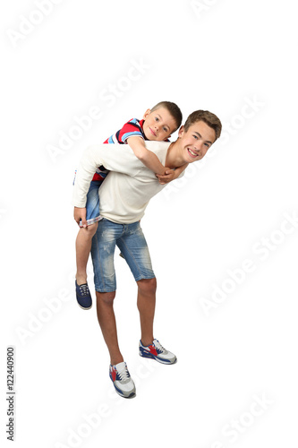 Older boy carries little brother on back isolated on white background