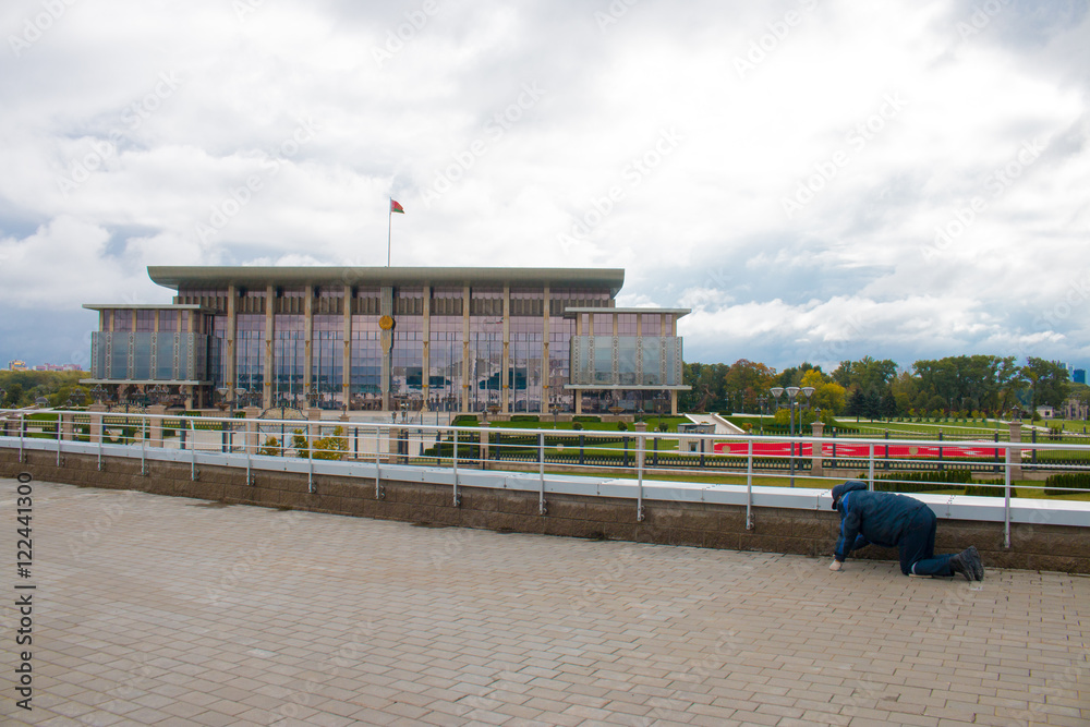 The cleaner collects the dust on the background of the Palace of the President of Belarus