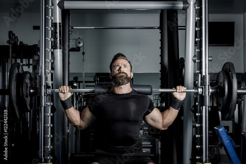 Hombre con grandes músculos levantando peso mientras entrena en el gimnasio. Ponerse en forma.