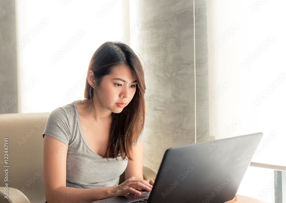 Pretty young asian woman using laptop while sitting in coffee shop. Pretty young asian woman using laptop while sitting in coffee shop.