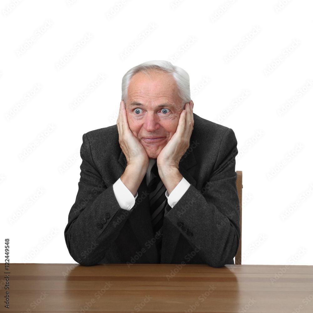Astonished senior man sits at table isolated on white background Astonished senior man sits at table isolated on white background