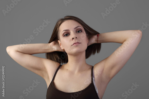 Young pretty woman posing with bare arms on dark gray background
