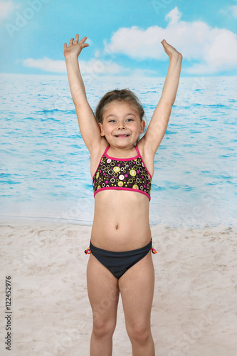 Cute little girl jumps on beach - summer, sun, sea, vacation, childhood concept