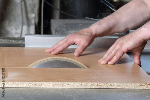 Carpenter cuts the board on rotating circular saw blade - Worker hands close up
