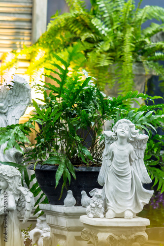 Statue of Cupid in cozy garden./ Statue Cupid and waterfall in cozy garden on summer. 
