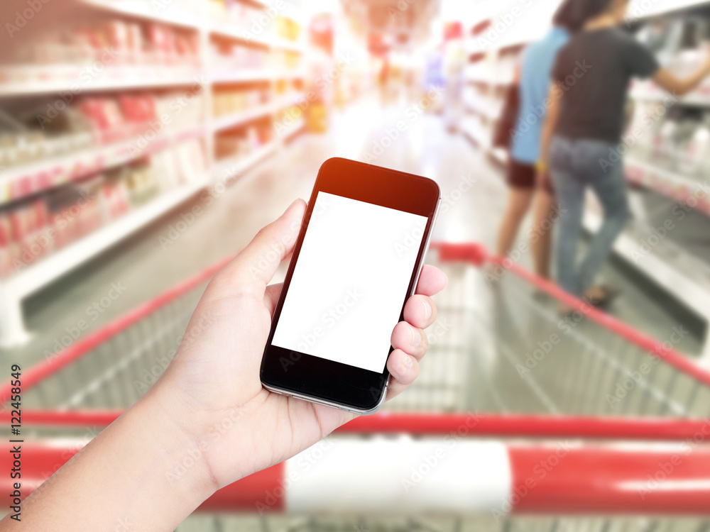 Female hand holding mobile smart phone on Supermarket blur backg Female hand holding mobile smart phone on Supermarket blur backg