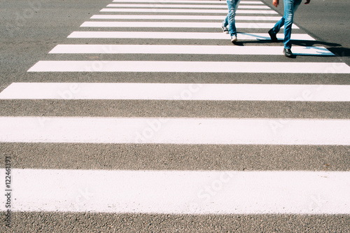 Men running on pedestrian zebra. Two guys in jeans crossing road on walk cross. Busy people, city life, safety walking