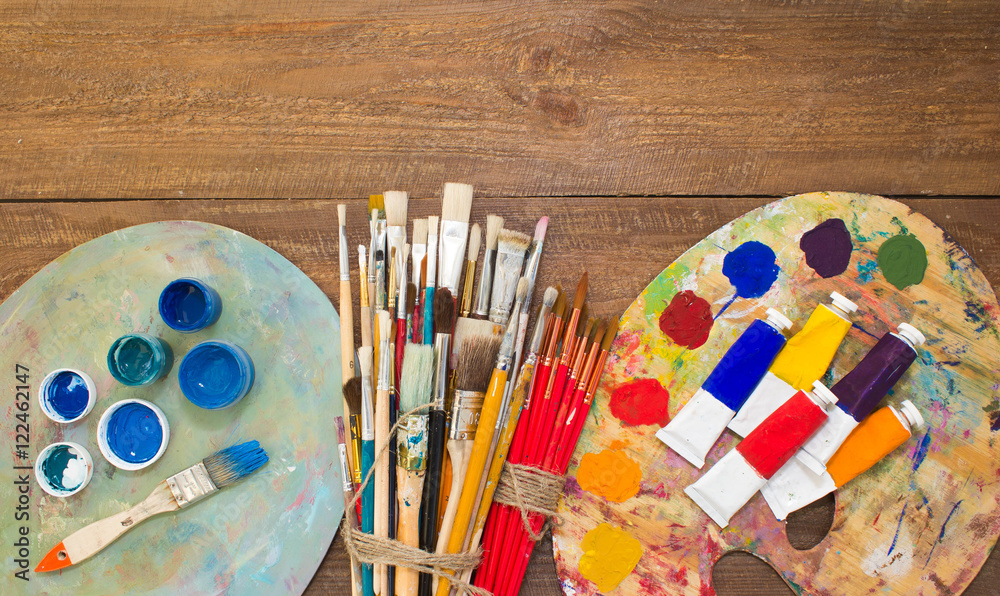 Naklejka premium Paints, brushes and palette on the colorful background. The workplace of the artist. Banner for school