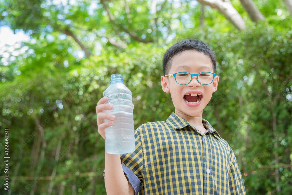 Young asian boy holding drink water bottle in park Young asian boy holding drink water bottle in park