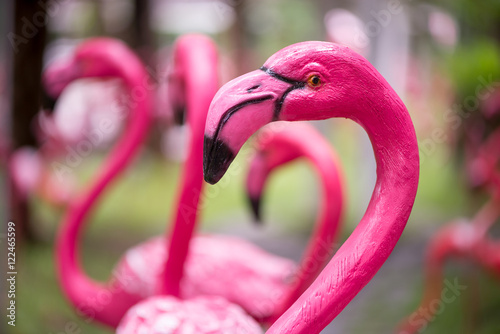 Close-up detail of a pink flamingo sculpture decorating a lawn, with a blurred out background. Home and garden decoration concept. photo