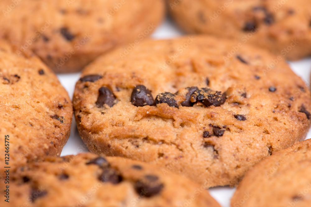 Macro closeup detail of multiple, freshly-baked chocolate chip cookies. Bakery background.