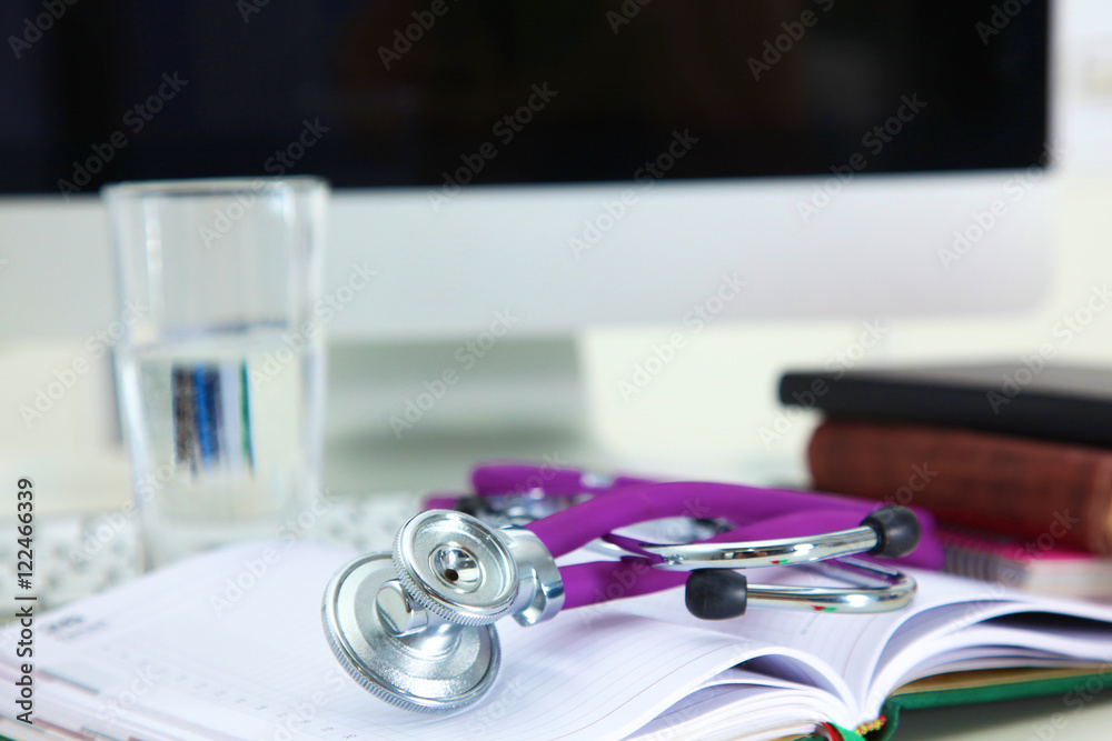 Stethoscope lying on a table an open book Stethoscope lying on a table an open book