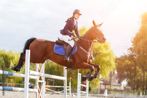 Young rider girl on horse show jumping competition