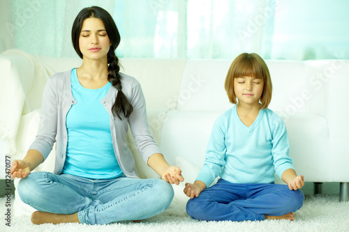 Mother with daughter meditating together at home