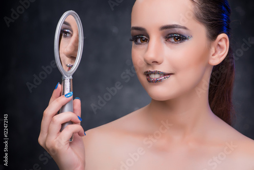 Young woman with small mirror in beauty concept