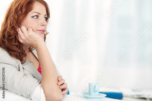 Young pretty woman sitting at cafe with a pensive expression