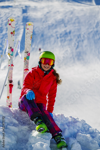 Girl sitting on the fresh powder snow at sunny day in mountains.