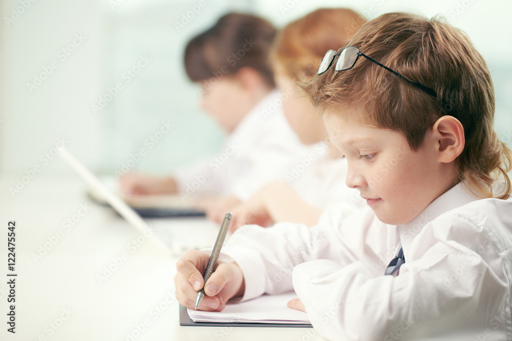Little boy making classwork with other pupils Little boy making classwork with other pupils