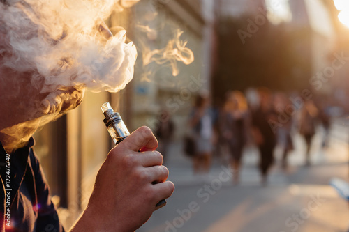 man using vape or electronic cigarette against the background of