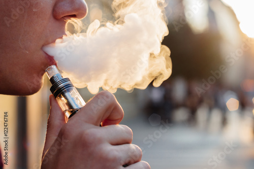 man using vape or electronic cigarette against the background of photo