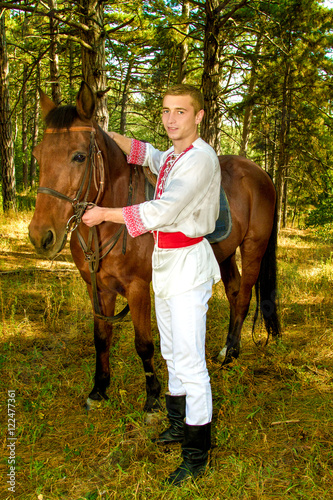  young Ukrainian with a horse in the forest