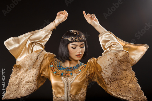 Fényképezés Beautiful woman like Egyptian Queen Cleopatra dancing against black background