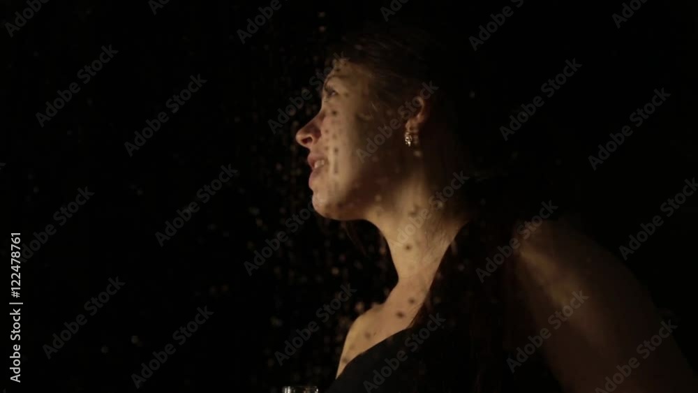 young sad woman behind the window with drops on it. lonely girl drinking brandy from the bottle and crying young sad woman behind the window with drops on it. lonely girl drinking brandy from the bottle and crying