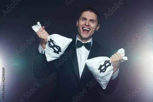 Cuadro en lienzo Portrait of mad businessman with two money bags laughing hysterically