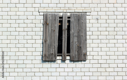 Boarded up window in a white brick wall