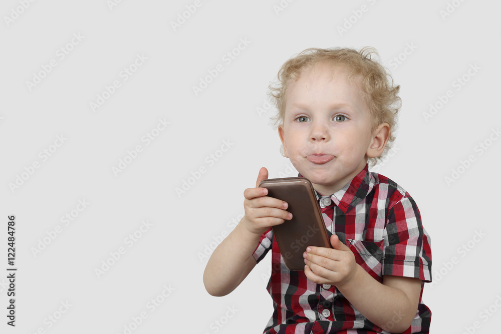 Little boy plays with smartphone on gray background with copy space - Modern gadgets and communication concept - Simplicity and usability Little boy plays with smartphone on gray background with copy space - Modern gadgets and communication concept - Simplicity and usability