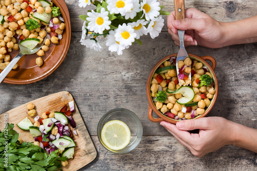 Person Eating a Ealthy Chickpeas Salad over a Grunge Wooden Tabl photo