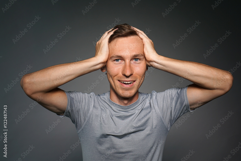 Portrait of a surprised caucasian man with hands on head.