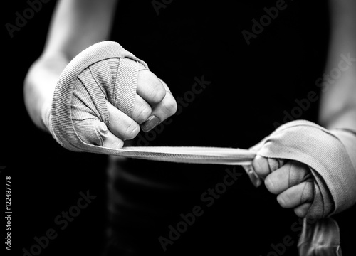 Woman is wrapping hands with pink boxing wraps photo